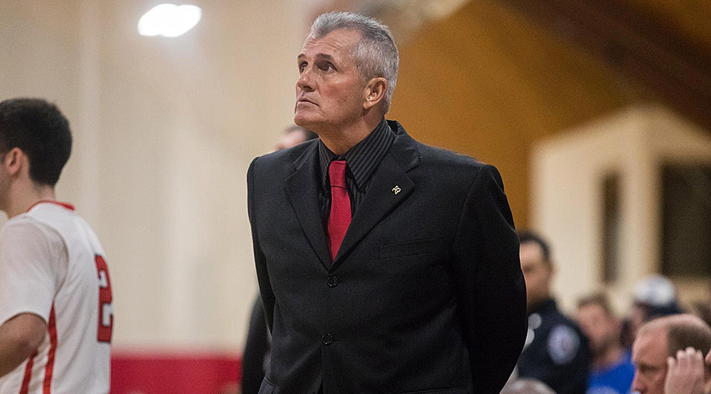 Paul Phillips on the sidelines in a dark suit and red tie. (Clark athletics photo)